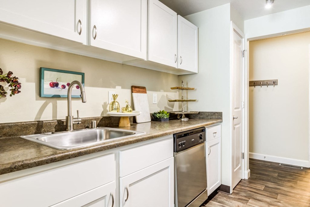 A kitchen with white cabinets and a stainless steel sink.
